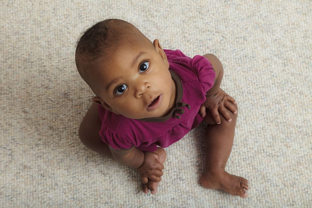 Petite fille rieuse sur un tapis