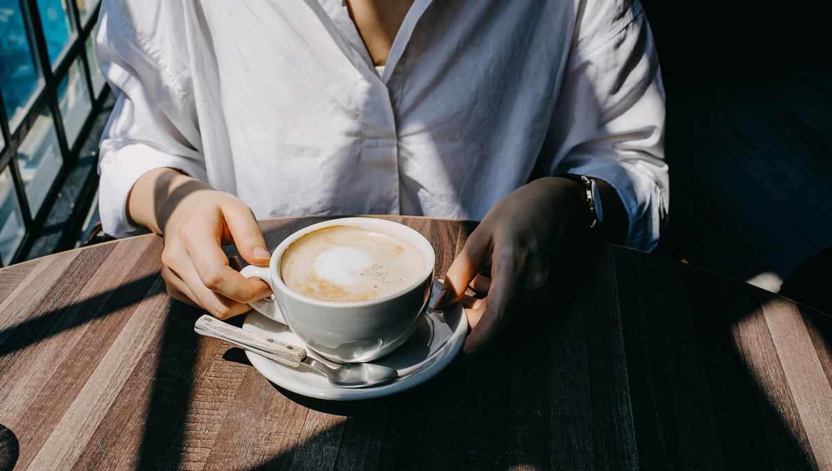 Main tenant une tasse de café au lait