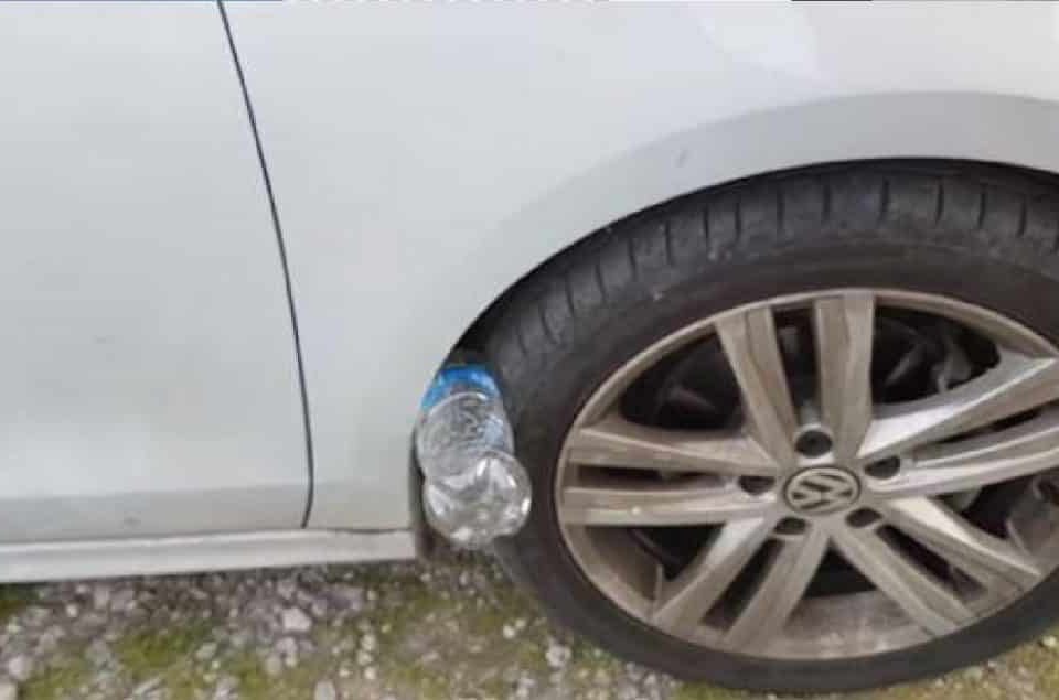 Bouteille en plastique coincée sous un pneu de voiture