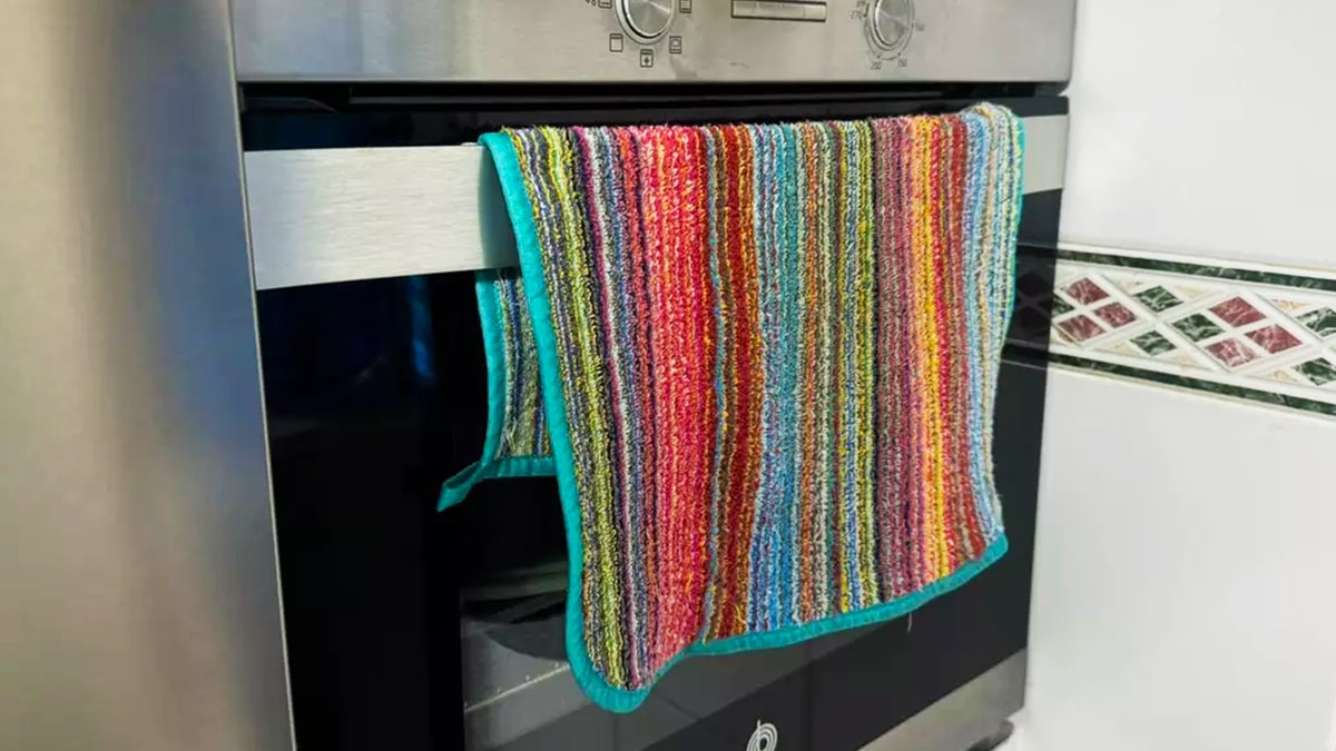 Torchon accroché à la porte d'un four allumé - une mauvaise idée