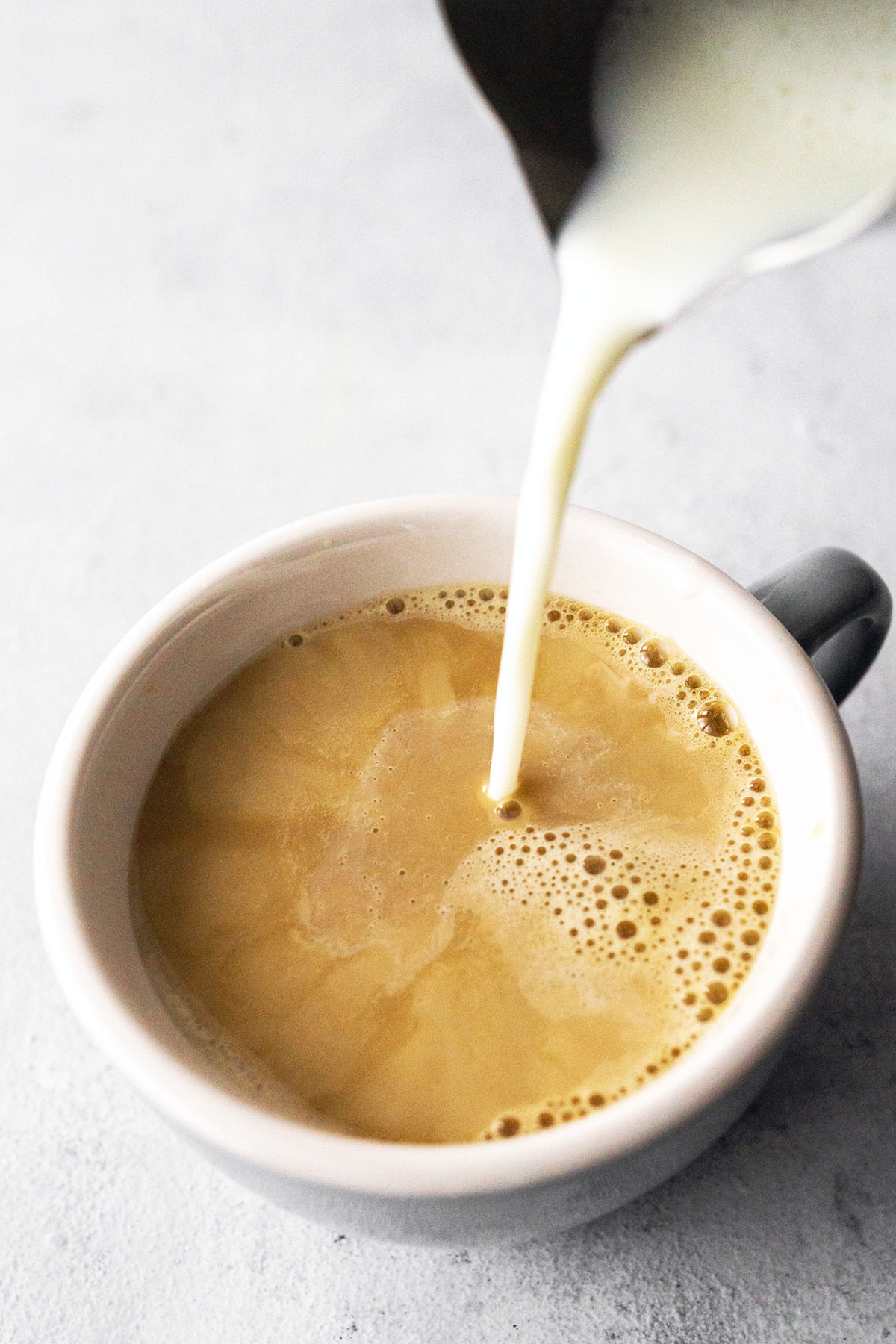 Personne versant du lait dans un café