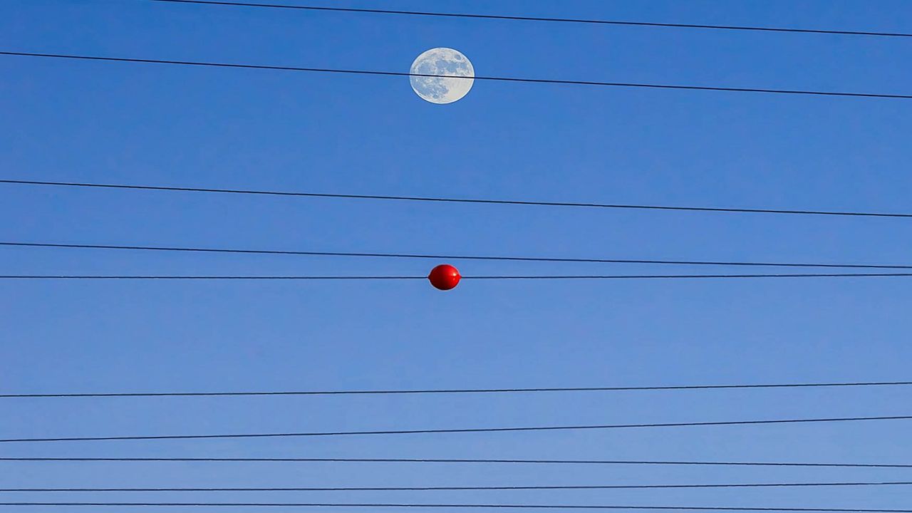 Paysage avec lignes électriques et boules de signalisation sous un ciel bleu