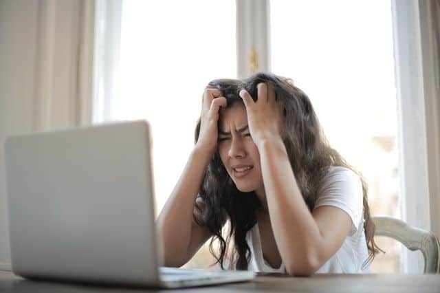femme se tenant la tête devant son ordinateur
