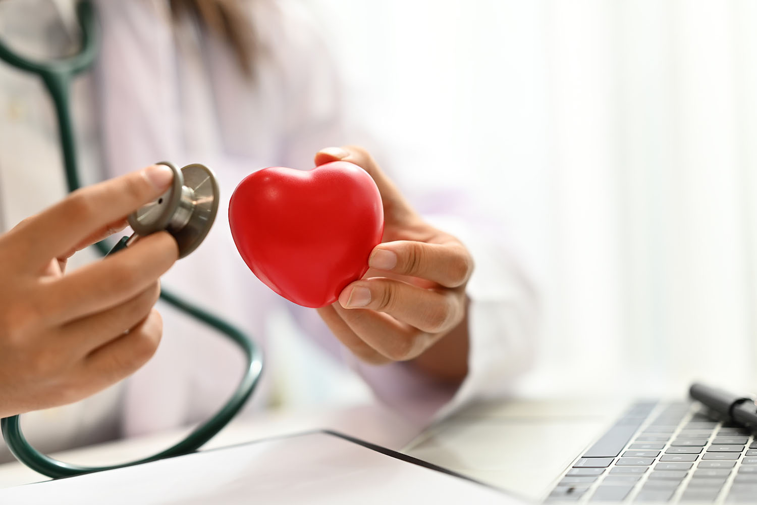 Médecin tenant un stéthoscope et un cœur rouge. Concept de contrôle cardiaque et de santé.