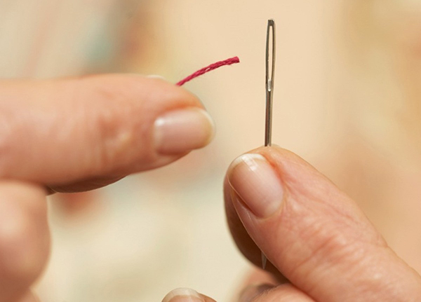 Femme tentant d'enfiler une aiguille avec difficulté