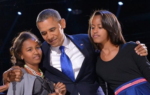 Barack Obama posant avec ses filles Malia et Sasha, tous souriants, lors d'un rassemblement