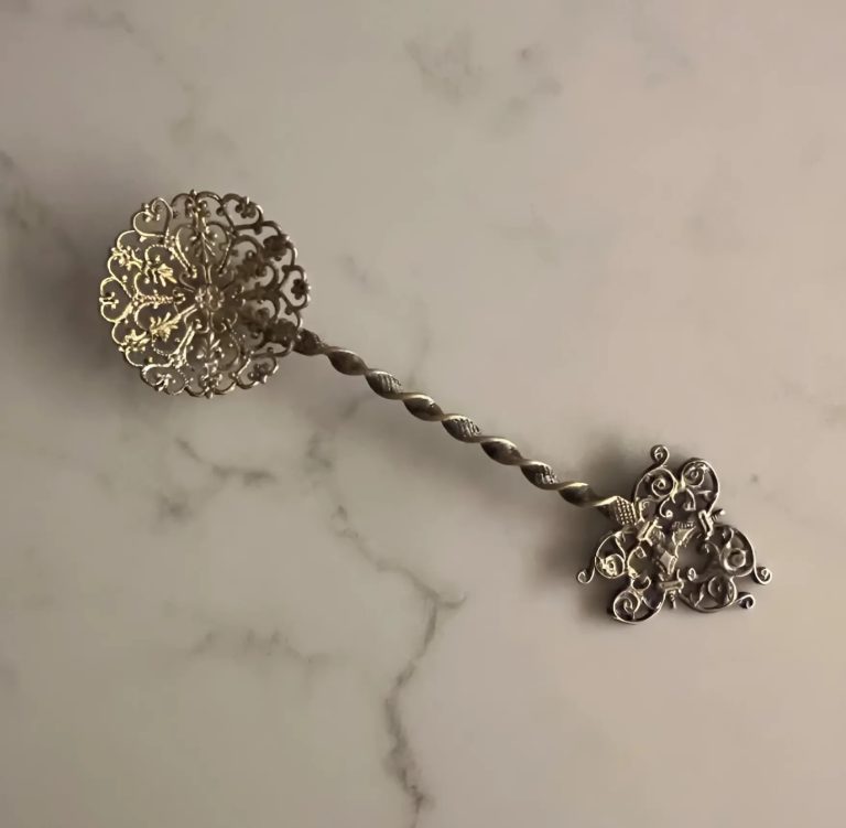 Cuillère à bonbons ancienne posée sur un tissu