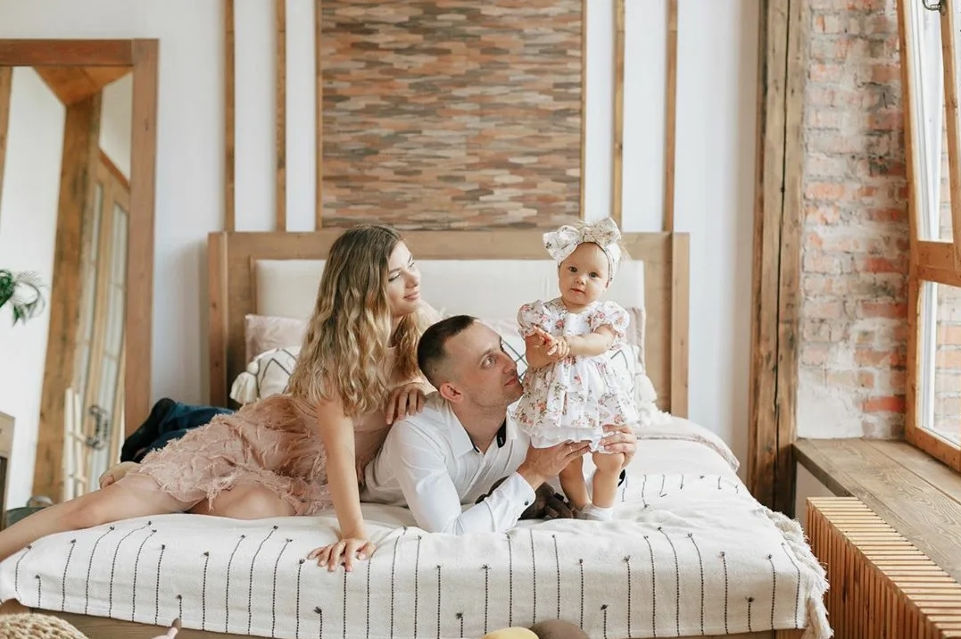 Une femme berce tendrement un nourrisson dans ses bras, dans une pièce chaleureusement éclairée.