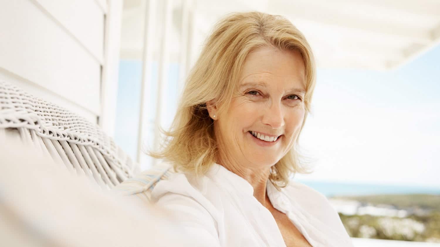 Femme souriante et sereine, les bras ouverts, devant un paysage lumineux