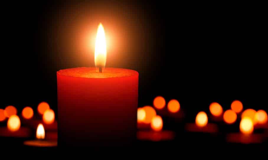 Bougies allumées lors d'une cérémonie en mémoire d'un défunt, évoquant le recueillement et la transmission.