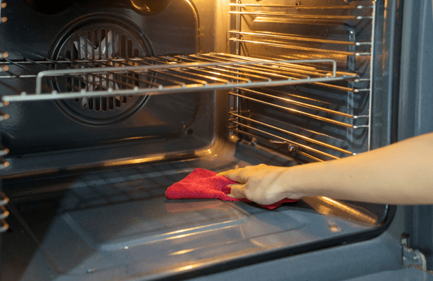 Personne nettoyant la vitre d'un four avec un chiffon