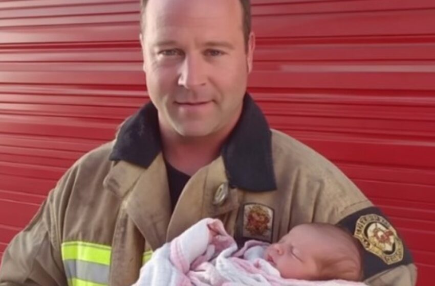 Un homme tenant tendrement un bébé dans ses bras, dans un intérieur chaleureux.