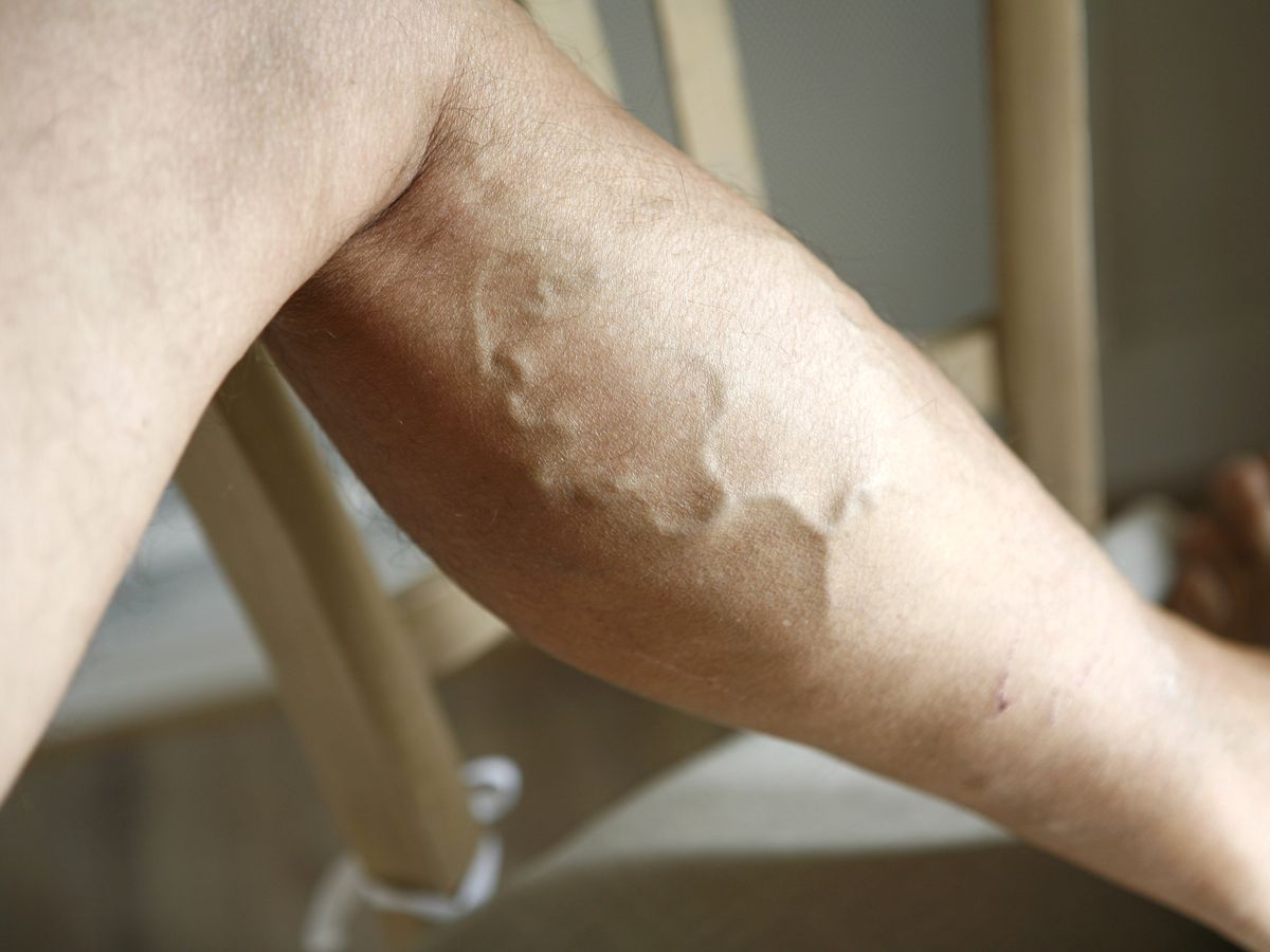 Femme souriante, les jambes relevées sur un canapé