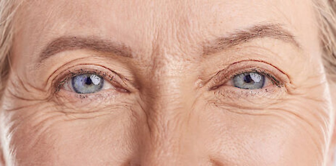 Femme souriante d'âge mûr posant la main sur sa joue, illustrant les changements cutanés