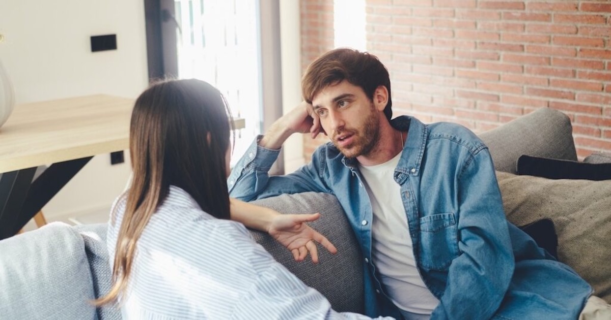 Un homme sourit malicieusement, assis à une table de cuisine