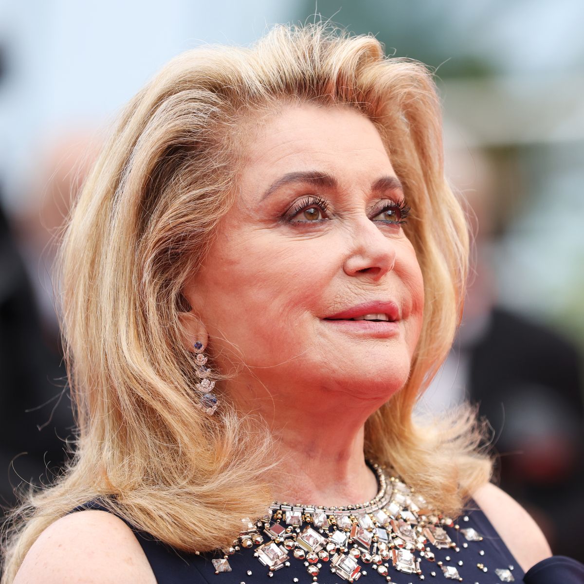 Catherine Deneuve souriante, avec un teint lumineux et naturel