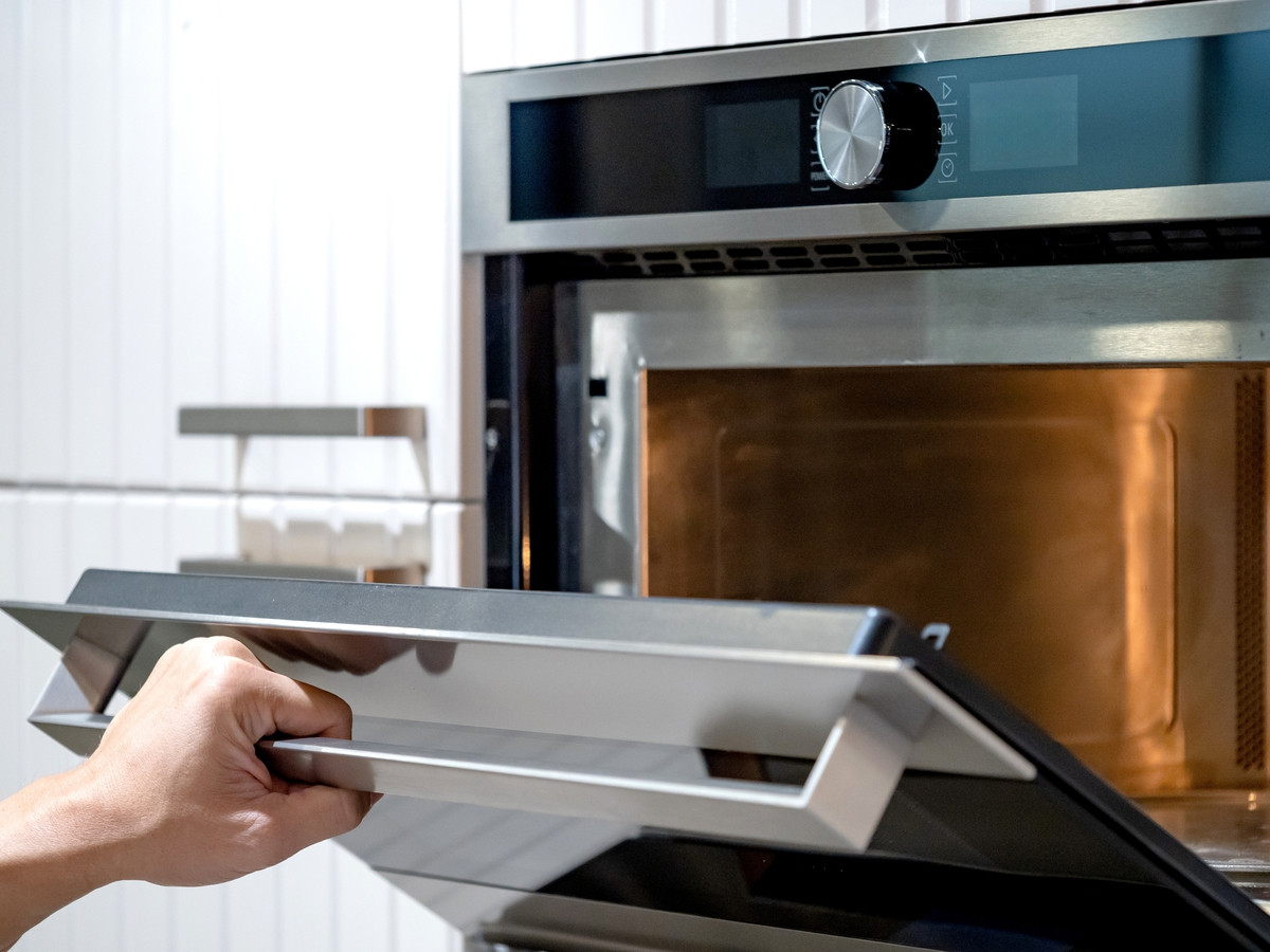 Femme nettoyant un four avec des produits adaptés